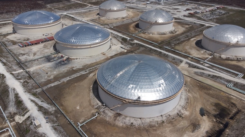 Techos de cúpula de aluminio sobre los grandes tanques de almacenamiento de Liwathon B.O.S., con puentes de tuberías y muros de cubeto.