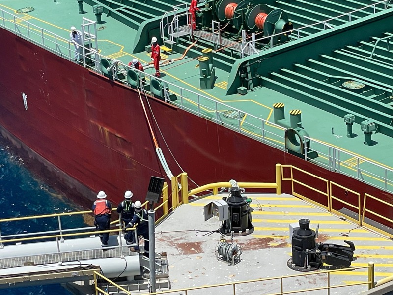A mooring team in hard hats and coveralls on a berthing dolphin as a tanker comes alongside the Sea Island, Grand Bahama.