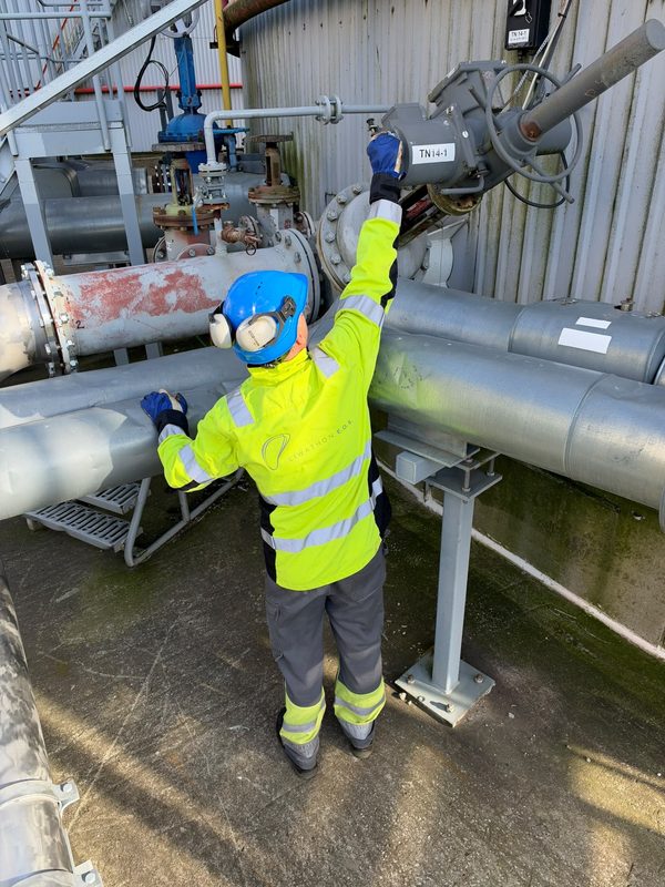 A Liwathon E.O.S. operator wearing a hard hat, ear defenders and gloves works a valve actuator.
