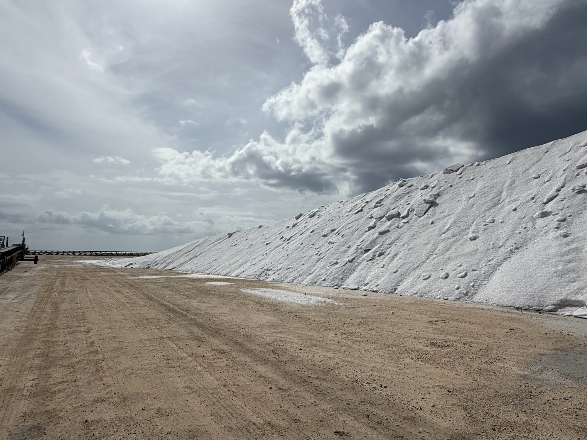 The long flank of the salt stockpile at the Lusca Salt works on Great Inagua, under a towering cumulus sky.