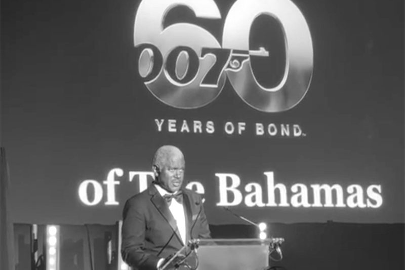 A speaker in black tie at a lectern in front of a screen reading “60 Years of Bond” and “of The Bahamas”, at the 52nd Independence Anniversary reception in London, July 2025.