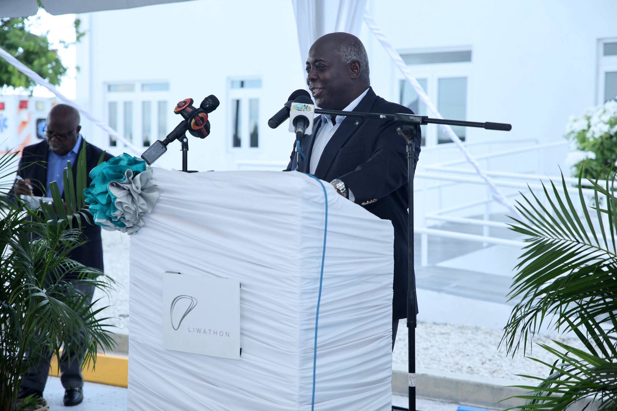 El primer ministro de las Bahamas habla en un atril cubierto de blanco con el logotipo de Liwathon durante la inauguración oficial de Liwathon B.O.S. en Gran Bahama, junio de 2024.